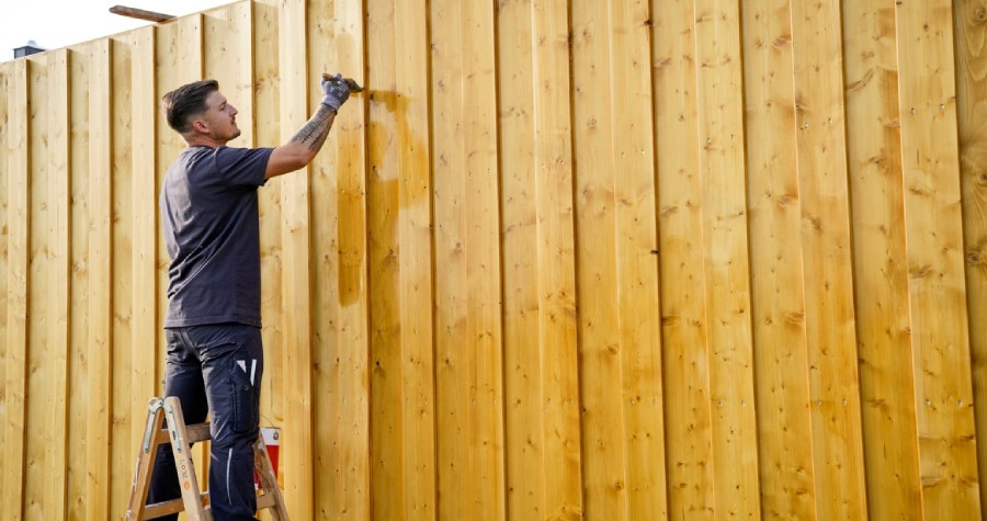 Een houten schutting die wordt behandeld met HK Lazuur plus